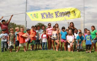 Group shot of children holding a banner that says Kid Kamp